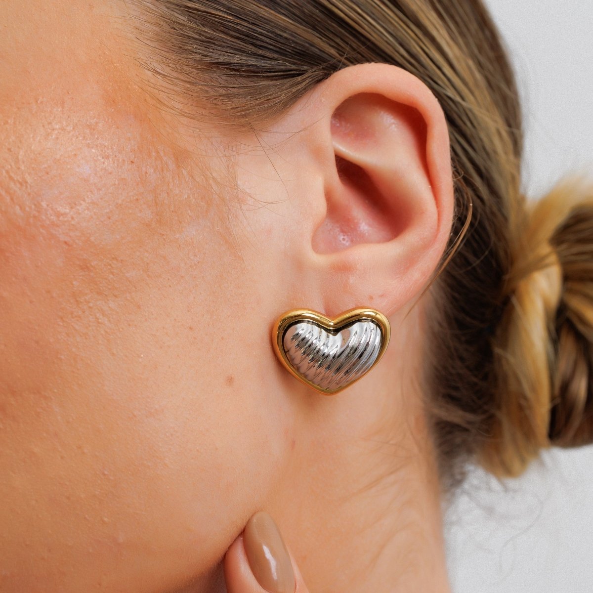 Heart-shaped stud earrings with a mix of gold and silver plating.